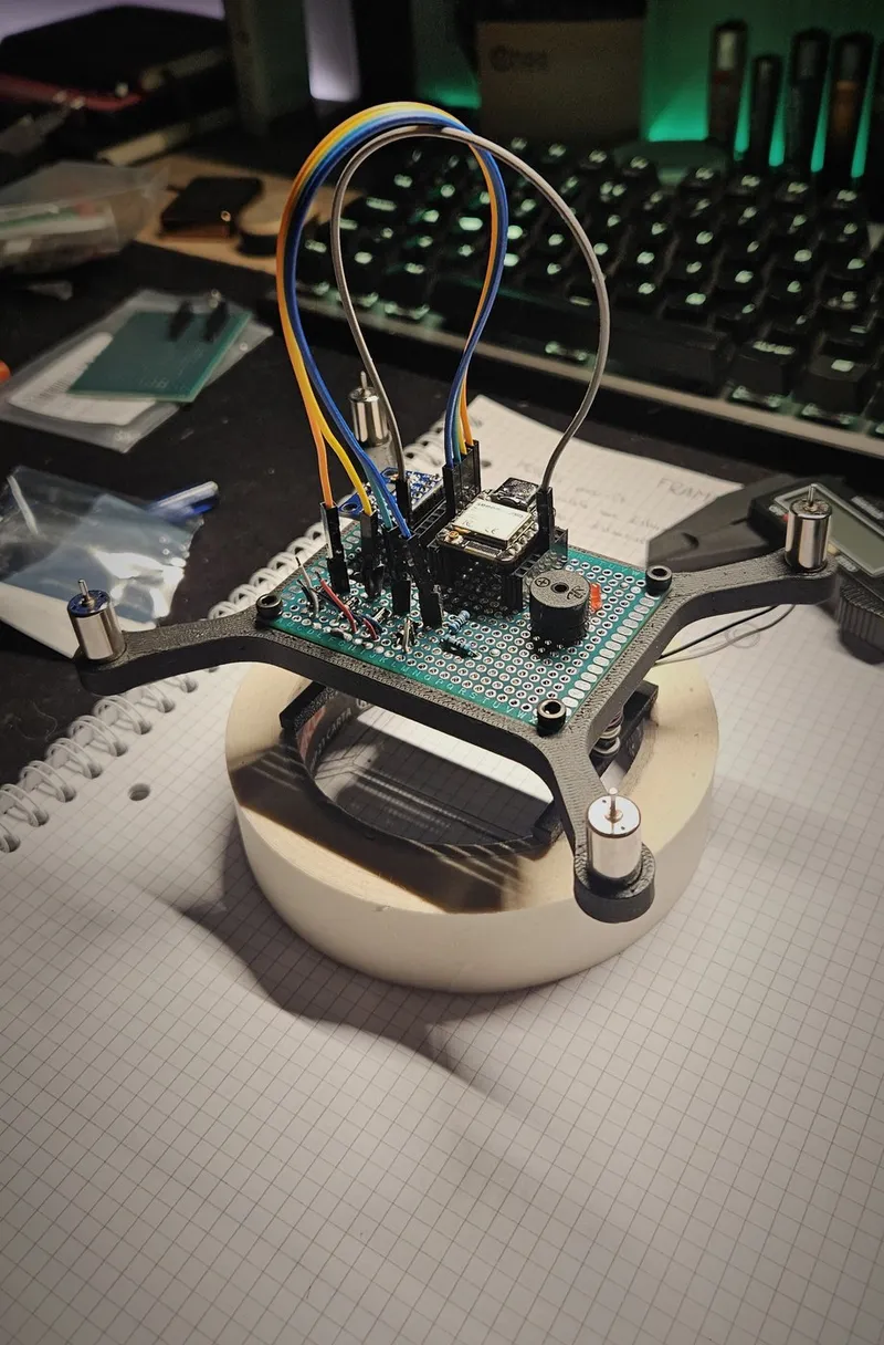 Assembled airframe on a 3D-printed stand for safe bench testing with the propellers removed: 3D-printed X-frame, coreless 8520 motors and the perfboard flight controller.